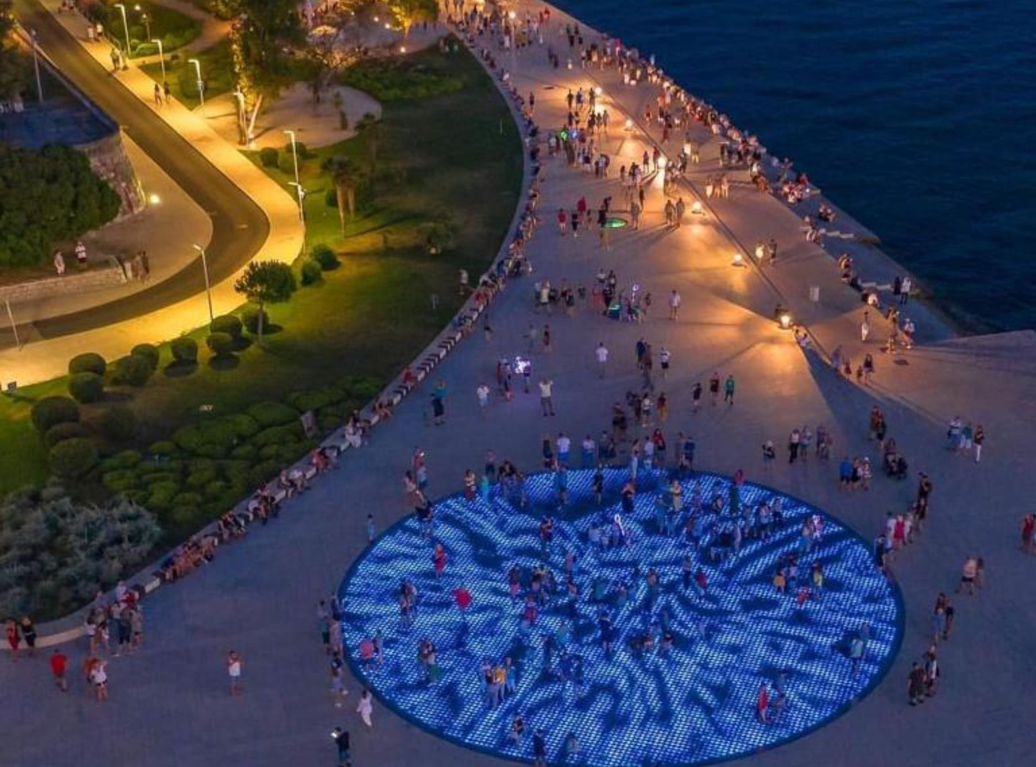 Vue aérienne d’une place publique avec une installation lumineuse circulaire à DEL et un chemin sinueux.