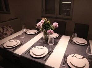 A dining table set with plates, cutlery, and a vase of flowers.