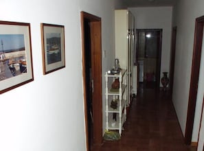 A narrow hallway with a white shelf unit against the wall, a door leading to another room, and a framed picture on the wall. - Casa Dolce Mare (Pasman)