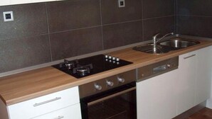 A modern kitchen with white cabinets, a wooden countertop, a built-in oven, and a stainless steel sink. - Casa Dolce Mare (Pasman)
