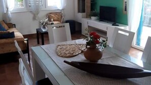 A dining area with a table set for two, a vase with flowers, and a television on a stand. - Casa Dolce Mare (Pasman)