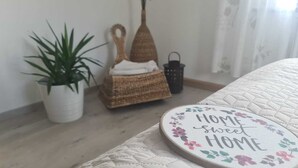 Ett välordnat sovrum med en säng, ett sängbord, en krukväxt, en flätad korg och en liten lykta.
