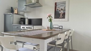 Ett modernt kök med en central köksö, vita skåp och en spis i rostfritt stål.
