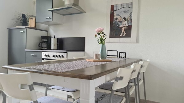 Une cuisine moderne dotée d’un îlot central, de meubles blancs et d’une cuisinière en acier inoxydable.