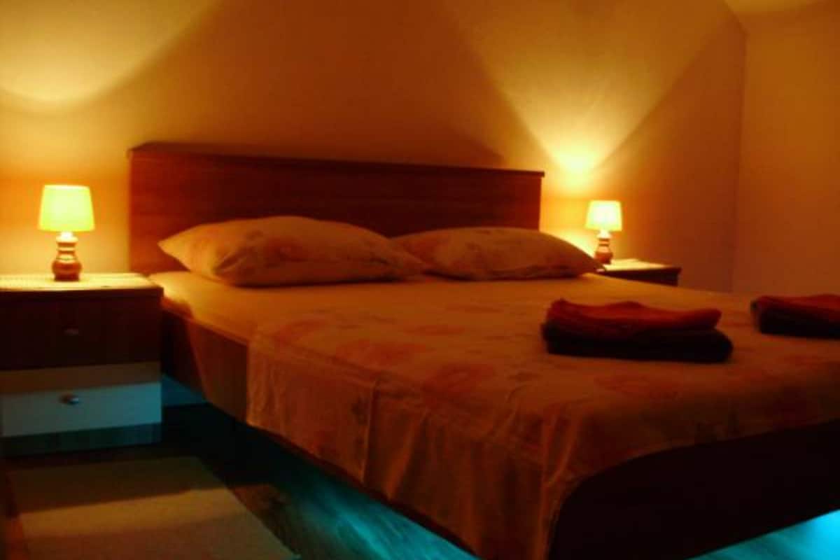 Ein Schlafzimmer mit einem Bett, zwei Nachttischen mit Lampen, einem kleinen Beistelltisch und einem Teppich.