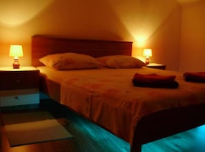 Un dormitorio con una cama, dos mesitas de noche con lámparas, un aparador y una pequeña alfombra.