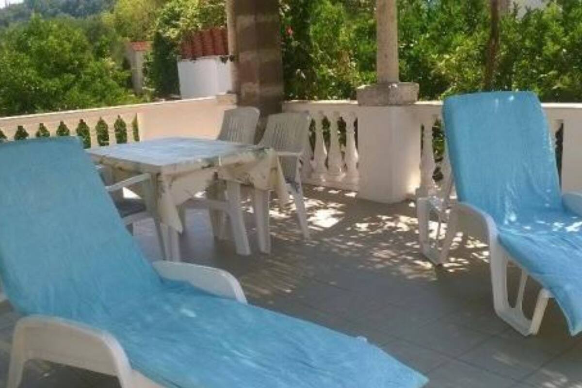 Eine Terrasse mit Gartenmöbeln, einem Tisch und einem Blumentopf.