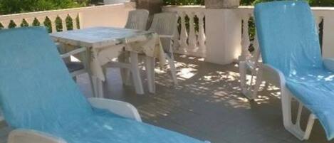 Une terrasse avec des meubles d’extérieur, une table et un pot de fleurs.