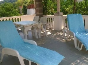 Una terraza con mobiliario exterior, una mesa y una planta en maceta.