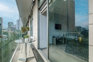 A modern balcony with a glass railing, a small table with chairs, and a view of a cityscape. - 2BR Luxury Stay Mundial 2026 Skyline Views (Mexico City)