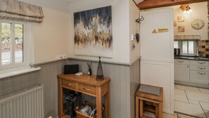 Una cocina acogedora con techo de vigas de piedra, una mesa de madera rústica y un cuadro en la pared.
