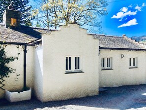 A traditional building with a white stucco exterior, a tiled roof, and a small window with a white frame. - The Dove Cot (Ambleside)