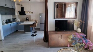 Cozinha moderna com armários cinza, uma ilha central e um espaço de refeições com um banquinho de bar.