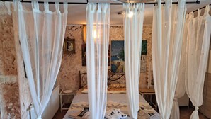 A bedroom with a bed, white curtains, a painting on the wall, and a small table. - Beautiful Unique Family Villa Emily (Opatija)