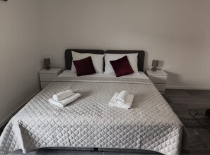 A neatly made bed with a quilted bedspread, two pillows, and two rolled towels on the bed. - Apartments Tourist Port (Dubrovnik)