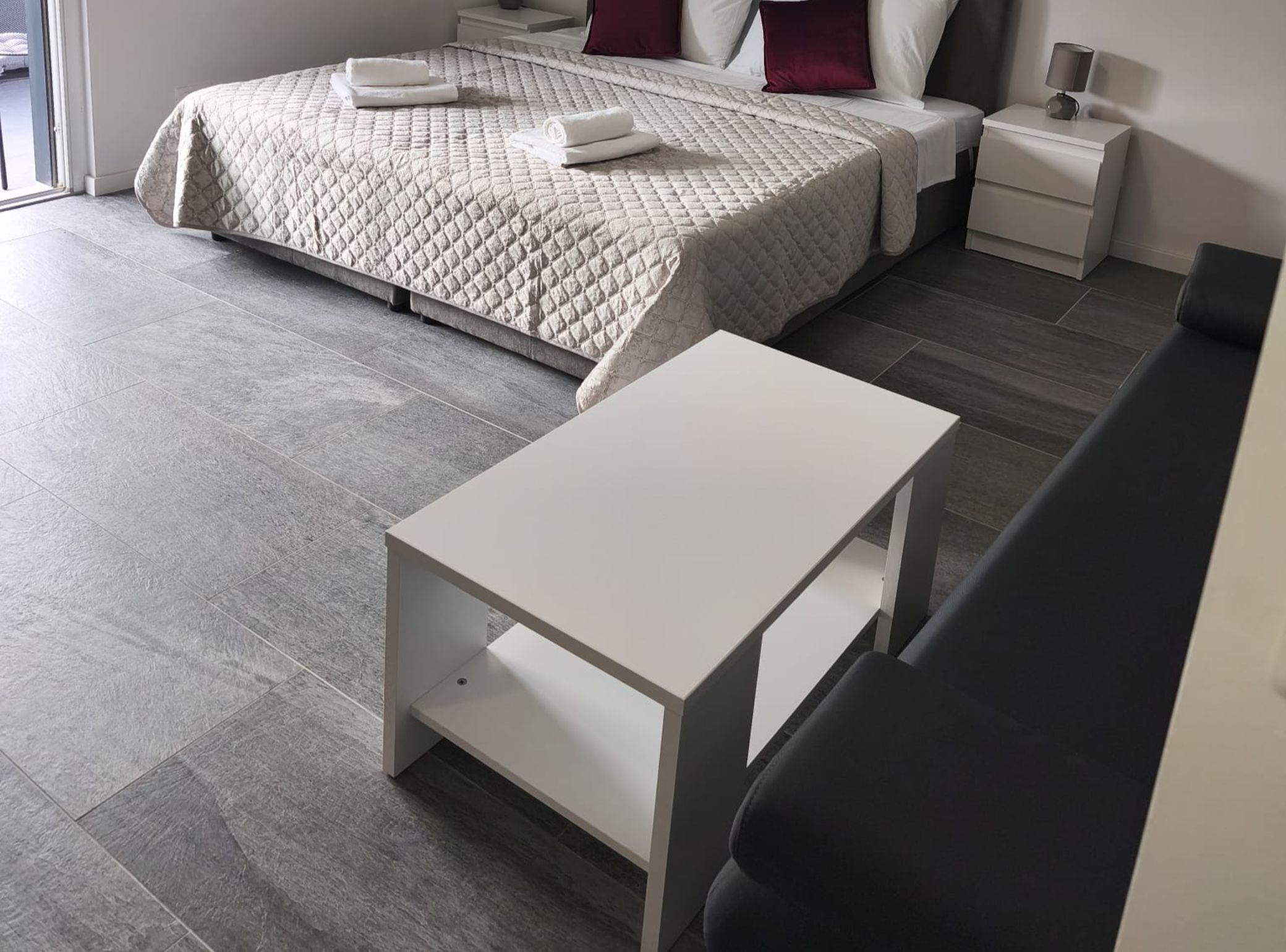 A modern bedroom with a bed, a bedside table, and a small white table in the foreground.
