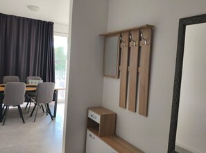 A modern room with a dining table, chairs, a small desk, a mirror, and a wardrobe. - Apartments Tourist Port (Dubrovnik)