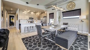 A modern kitchen with pendant lighting, a dining area with a table and chairs, and a living area with a sofa and ottoman. - The Gallery! Luxury Residence w/ Front Range Views (Monument)