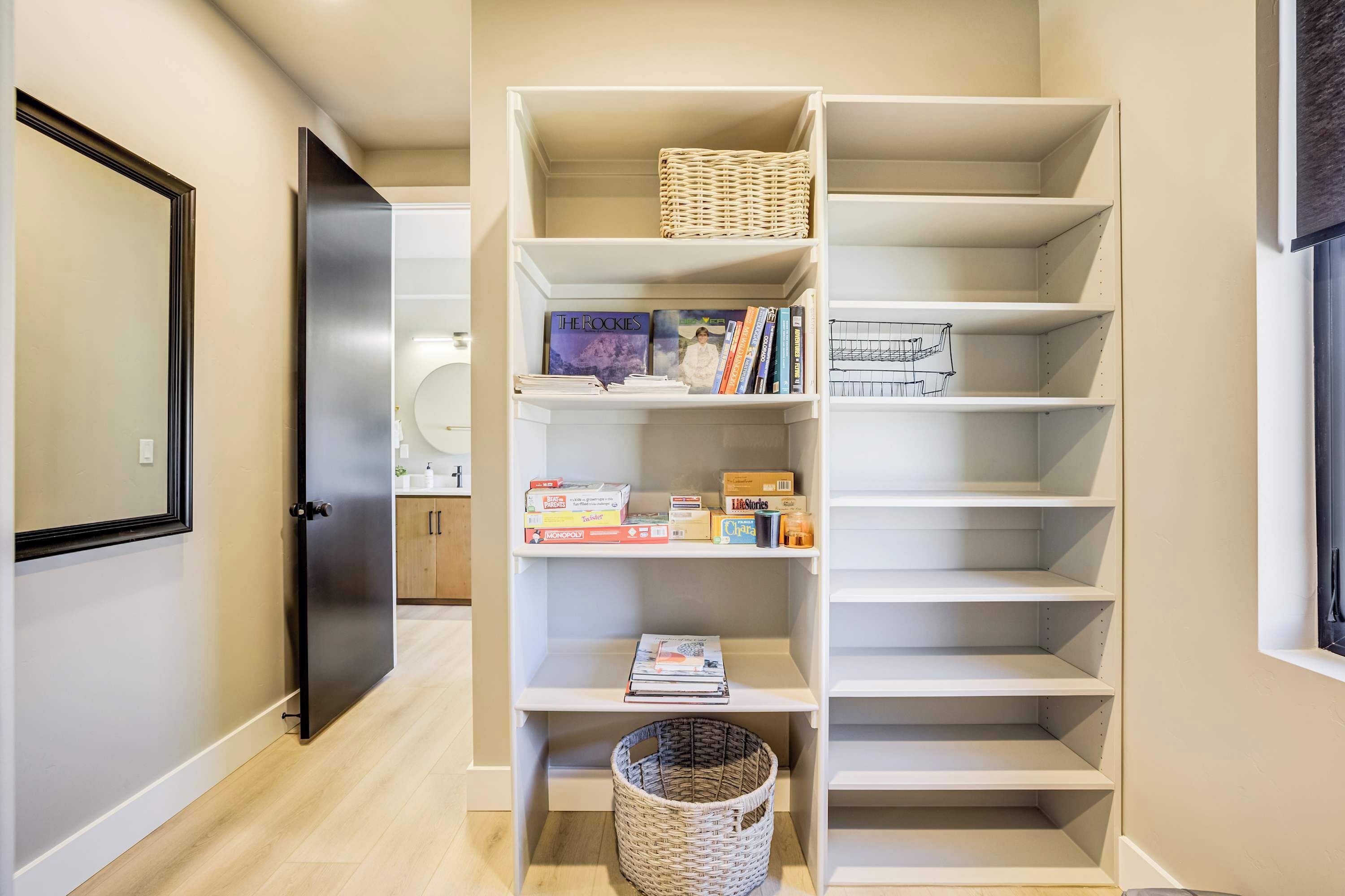 A hallway with a white shelving unit containing books, a wicker basket, and a wicker basket on the floor.