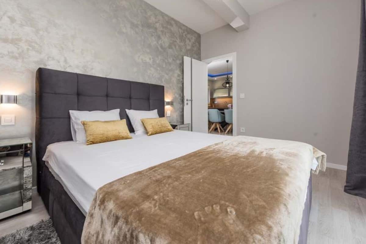 A modern bedroom with a large bed, a nightstand, and a built-in wardrobe.
