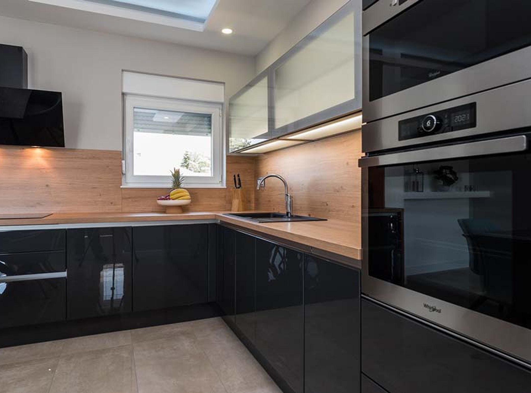 Eine moderne Küche mit schwarzen Schränken, einem Edelstahlbackofen und einem Fenster über der Spüle.