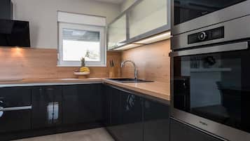 Una cocina moderna con gabinetes negros, un horno de acero inoxidable y un ventanal sobre el fregadero.