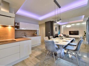 A modern kitchen with white cabinets, a wooden countertop, and pendant lighting. - Villa Marija Exclusive Stay (Sukosan)