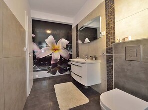 A modern bathroom with a large mirror, a white sink, and a toilet. - Villa Marija Exclusive Stay (Sukosan)