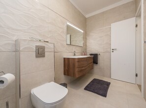 Un baño moderno con inodoro, lavamanos y ducha.
