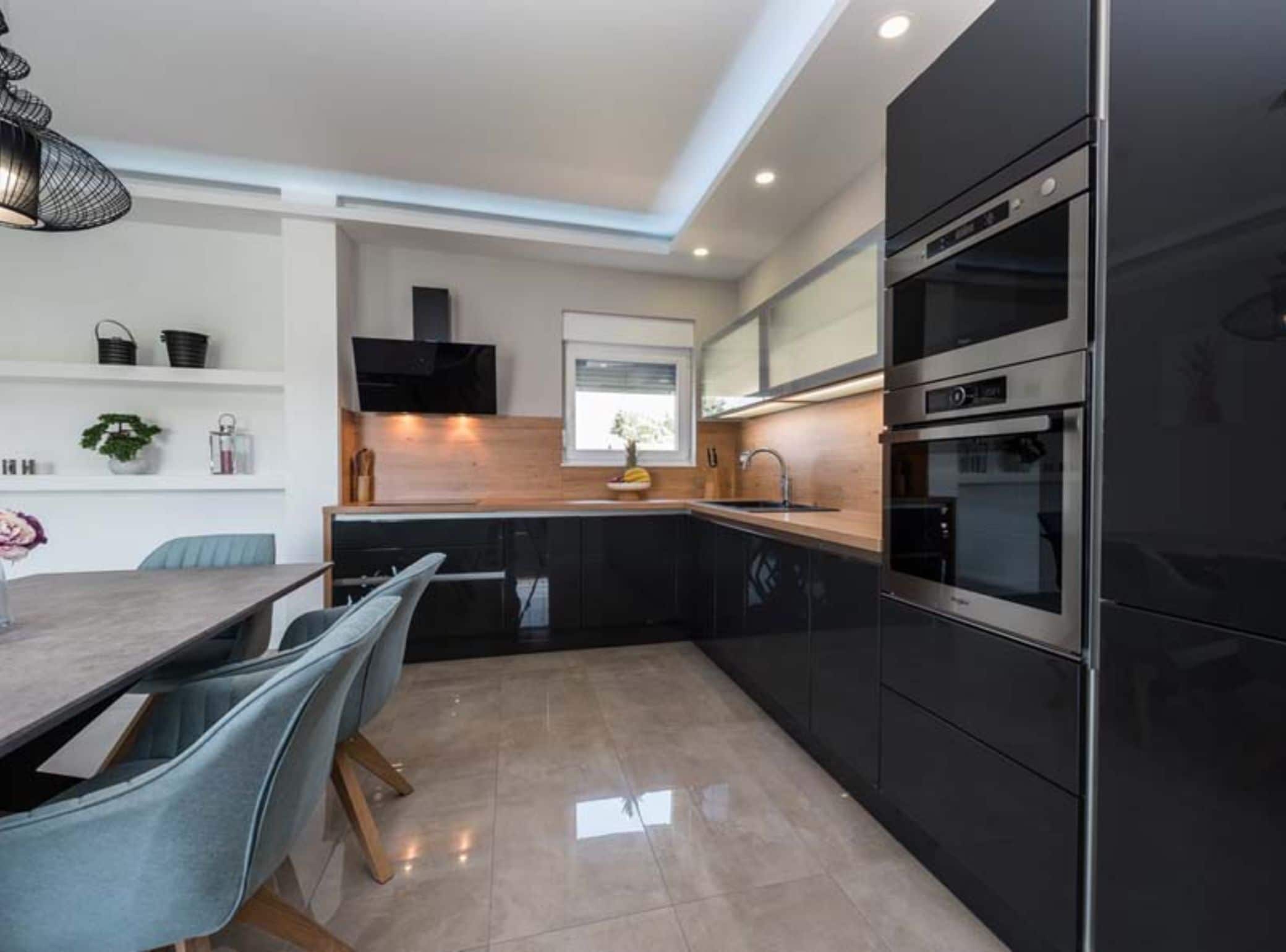 A modern kitchen with black cabinets, a stainless steel oven, and a wooden countertop.