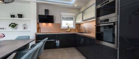 Una cocina moderna con armarios negros, horno de acero inoxidable y encimera de madera.