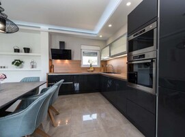 A modern kitchen with black cabinets, a stainless steel oven, and a wooden countertop.