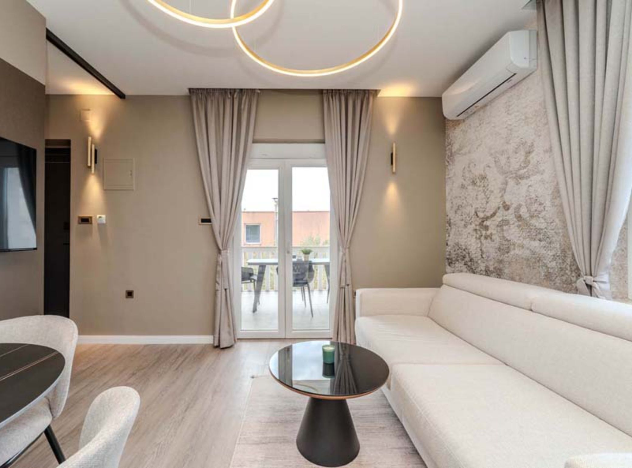 Un salon moderne avec un canapé, une table basse ronde et un coin repas comprenant une table et des chaises.