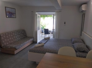Ein Schlafzimmer mit Bett, Sofa, Tisch und Blick ins Freie.