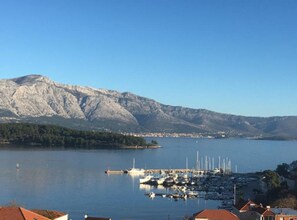 Ein Yachthafen mit vertäuten Booten, Bergen im Hintergrund und einem klaren Himmel.