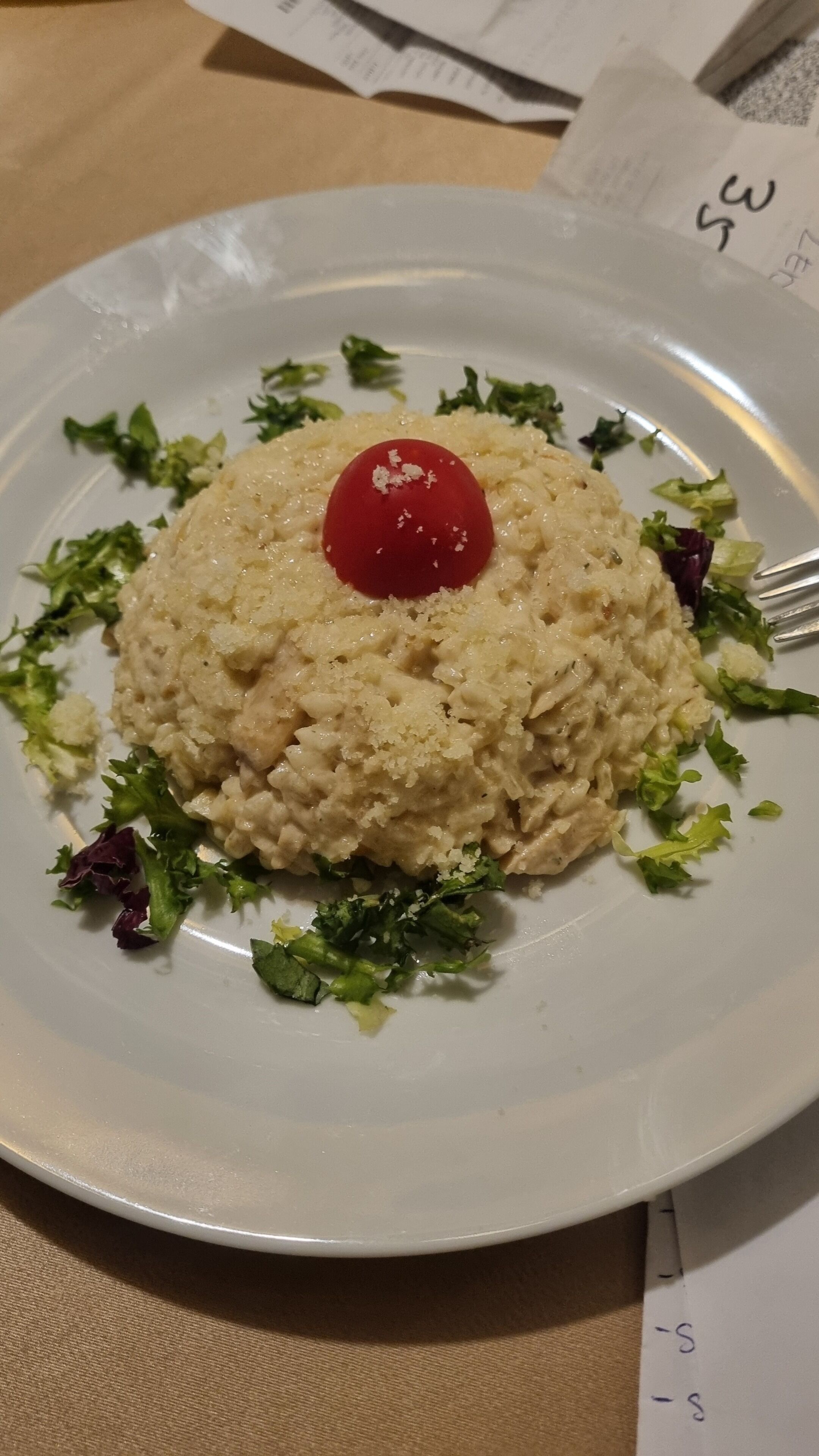 Une assiette de nourriture surmontée d’une cerise, le tout entouré de légumes verts.