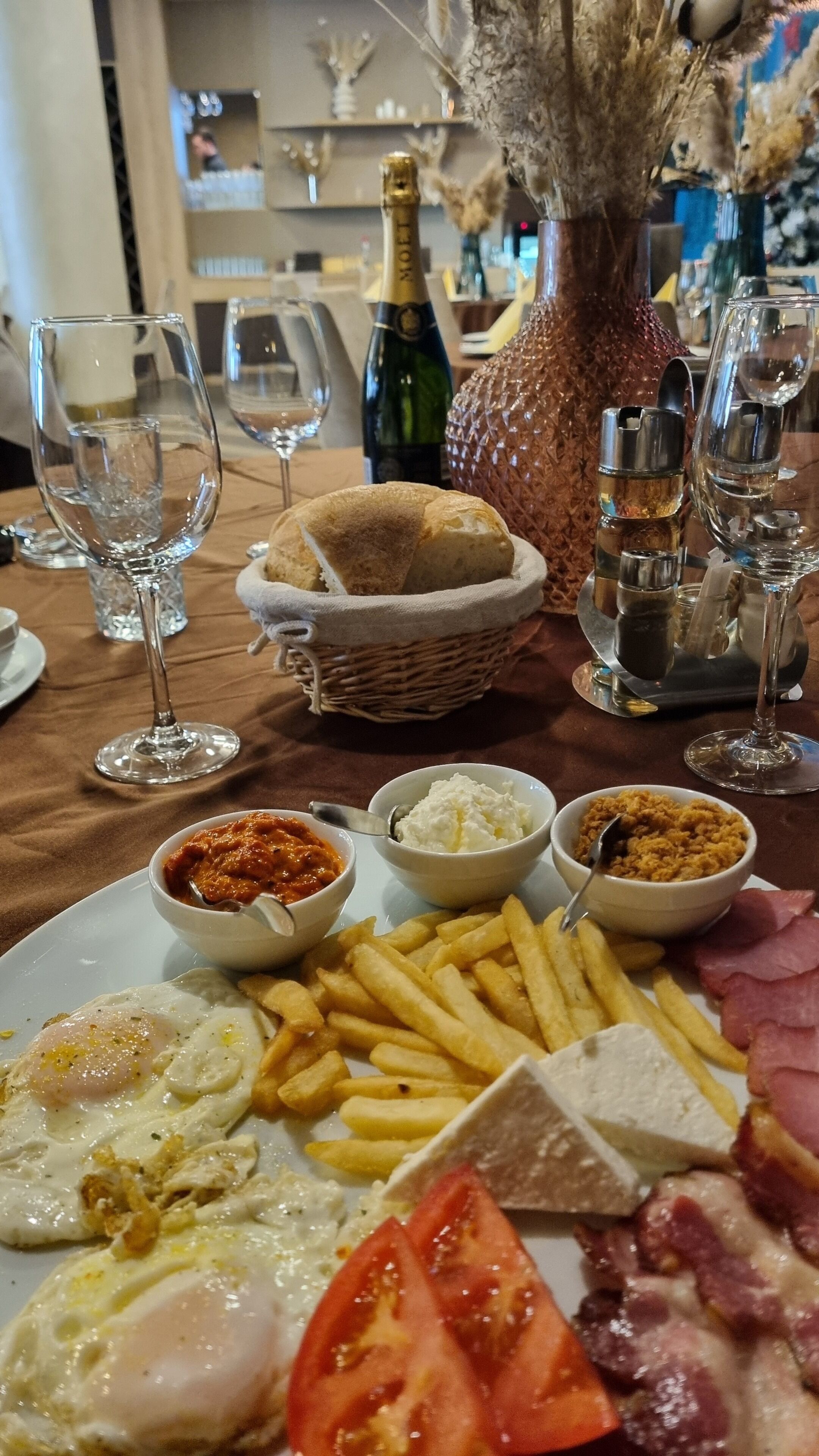 Ein Esstisch mit einer Schüssel Essen, darunter Eier, Pommes, Käse und Schinken.