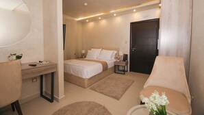 Quarto moderno com cama, mesas de cabeceira, escrivaninha, cadeira e banheiro.