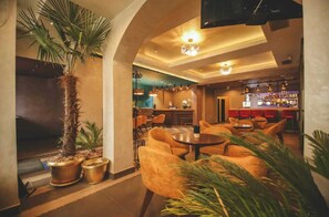 A lobby with a bar area, seating, and a large potted plant. - Decenija Hotel & Restaurant (Belgrade)