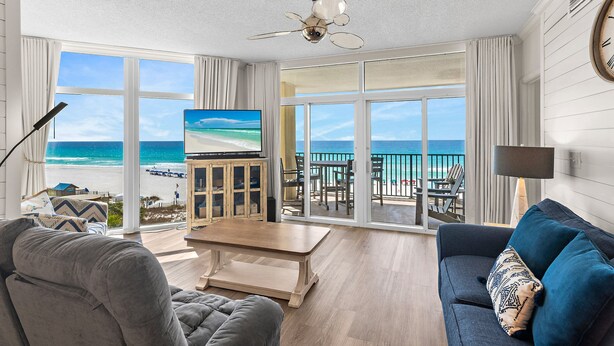 Un salon doté d’un grand téléviseur, d’un ventilateur de plafond et offrant une vue sur la plage.