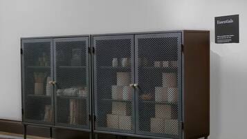Un meuble métallique à deux portes, doté d’une façade en treillis, est placé contre un mur uni.