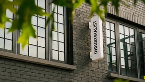 A building with a sign reading "INDUSTRIALIST" and large windows. - The Industrialist Hotel Brooklyn (Brooklyn)
