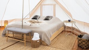 A cozy tented room with a bed, a bench, a small table, and a basket. - Nomad Greenland (Saqqaq)