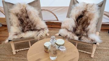 Two rustic chairs with fur upholstery, a round wooden table with salt and pepper shakers, and a woven mat on the floor.