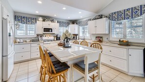 Una cucina moderna con mobili bianchi, un'isola centrale con posti a sedere e piastrelle decorative blu e bianche sulle pareti.
