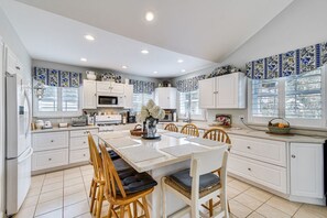 A modern kitchen with white cabinetry, a central island with seating, and decorative blue and white tiles on the walls.