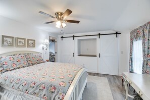 A bedroom with a bed, a ceiling fan, a wardrobe, and a desk.