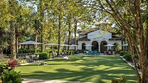 A courtyard with a lawn, outdoor seating, and a building with arches. - 2 Bedroom, Sleep 8, Marriott Lakeshore Reserve, Spring Break (Orlando)