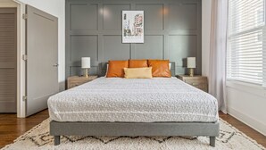 A bedroom with a large bed, grey walls, and a framed picture on the wall. - Private Rooftop | Modern Downtown + Large Space (Nashville)