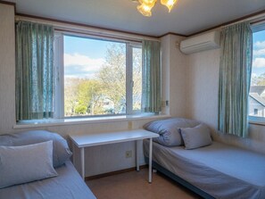 A room with two beds, a small table, and a window with curtains.
